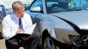 Insurance adjuster looking at a damaged car